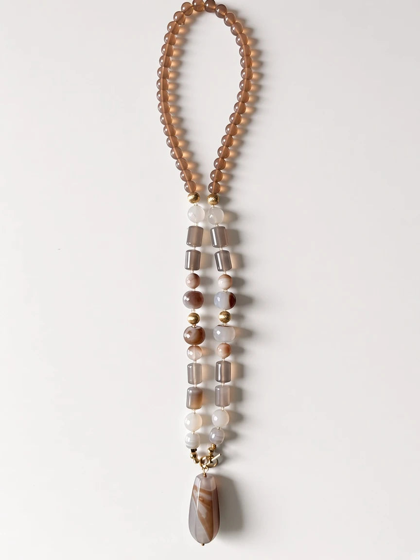 Hue La La Gems beaded statement necklace with taupe and cream agate beads and a teardrop pendant on a white background