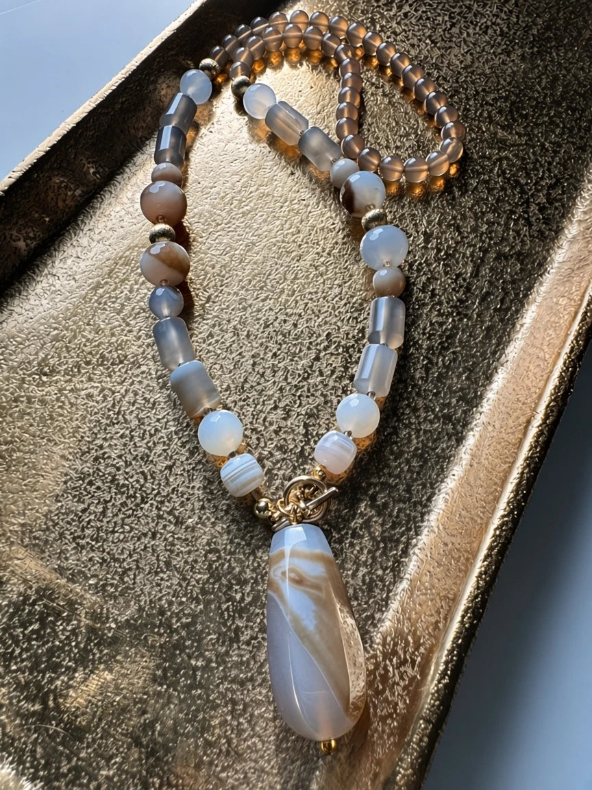 Hue La La Gems beaded statement necklace with a teardrop agate pendant, gold-tone hardware, and neutral earth tones.