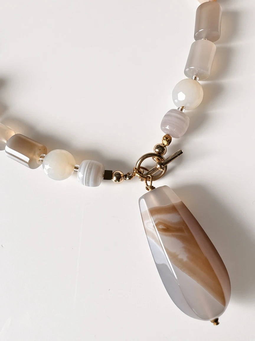 Hue La La Gems beaded statement necklace featuring natural taupe and cream agate beads with a teardrop pendant.