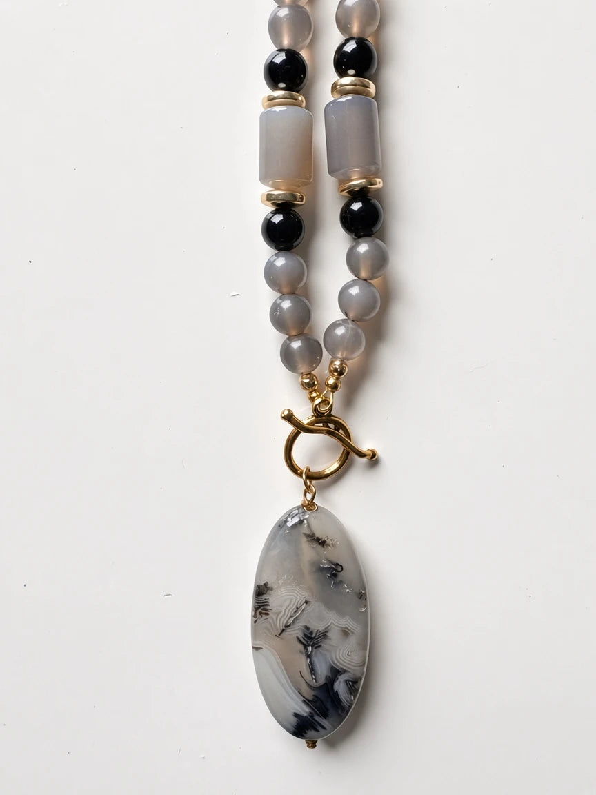Hue La La Gems beaded statement necklace featuring grey agate beads, black accents, and an oval gemstone pendant.