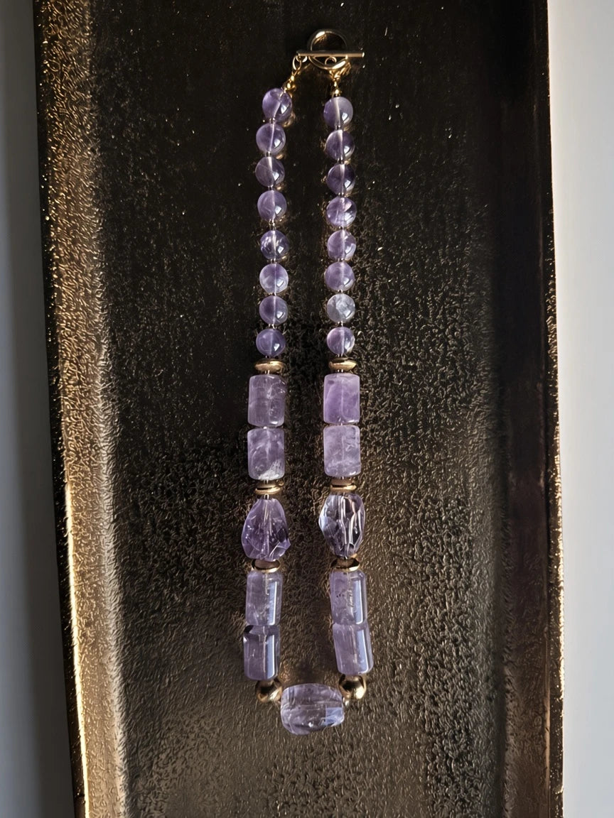 Hue La La Gems amethyst beaded statement necklace with gold-tone accents and a toggle clasp on a textured gold tray.