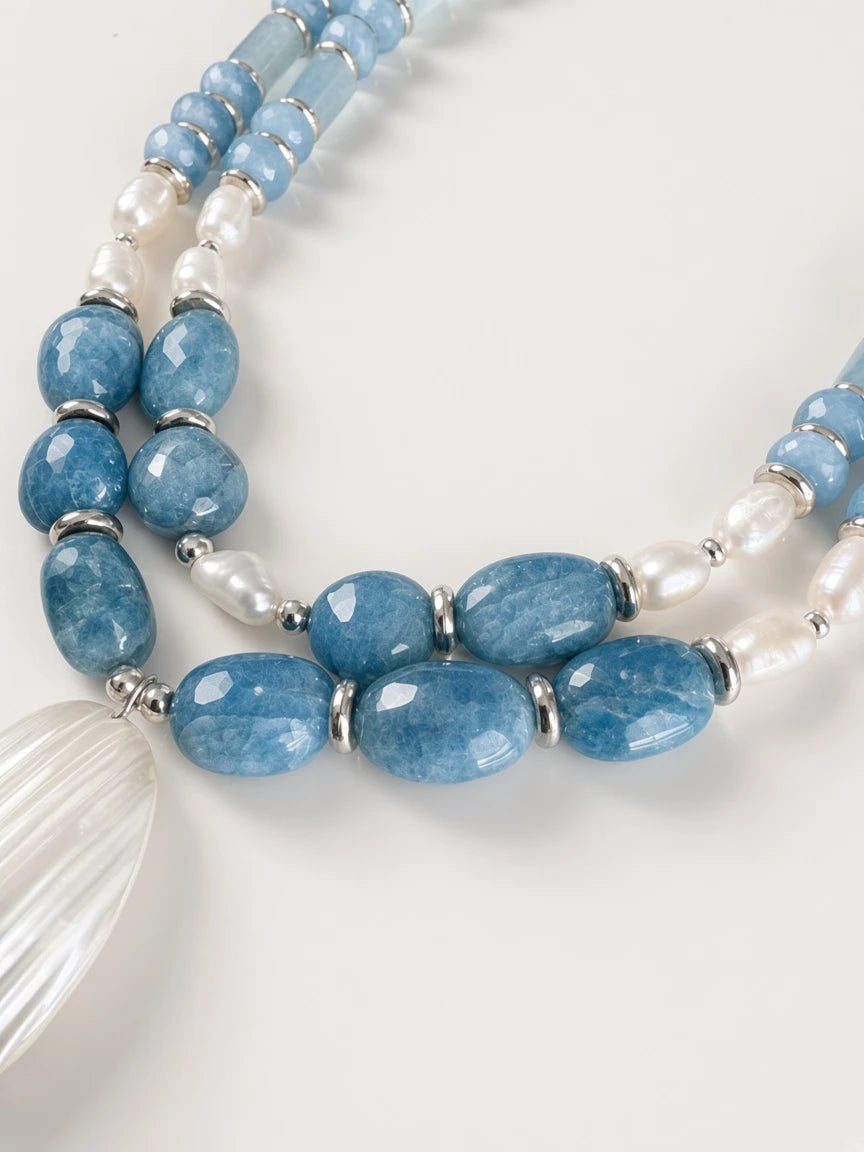Hue La La Gems multi-strand statement necklace with blue aquamarine beads, freshwater pearls, and a shell pendant.