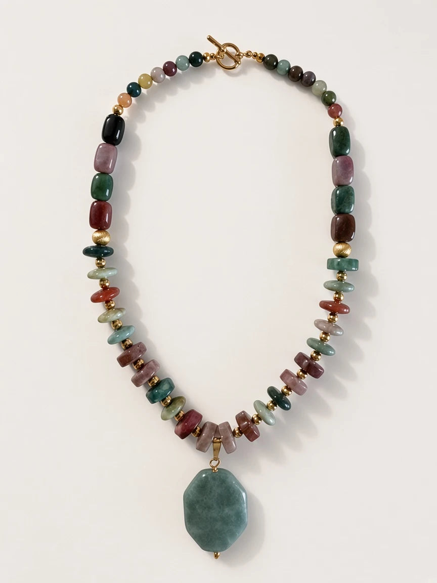 Hue La La Gems beaded statement necklace with multi-colored polished gemstones, gold-tone spacers, and a green pendant.