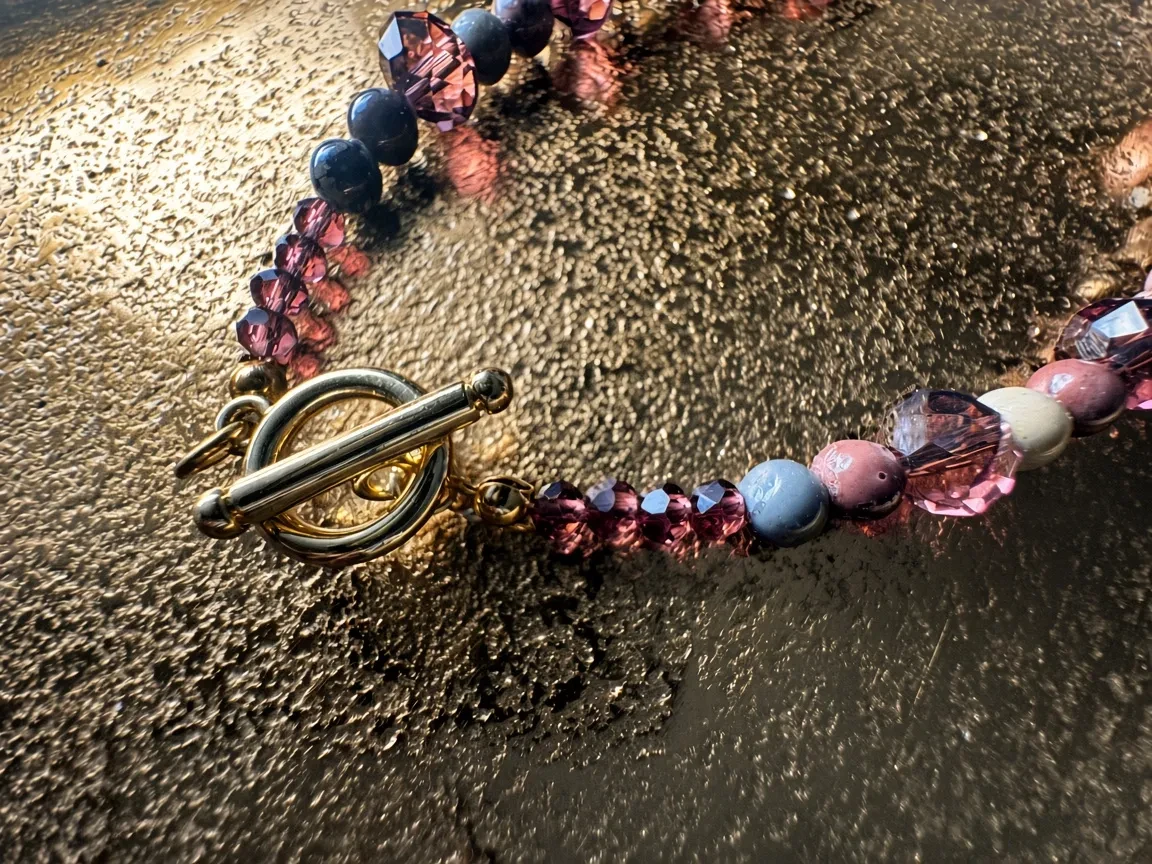 Hue La La Gems artisan beaded necklace featuring faceted purple crystals, matte pastel beads, and a gold toggle clasp.