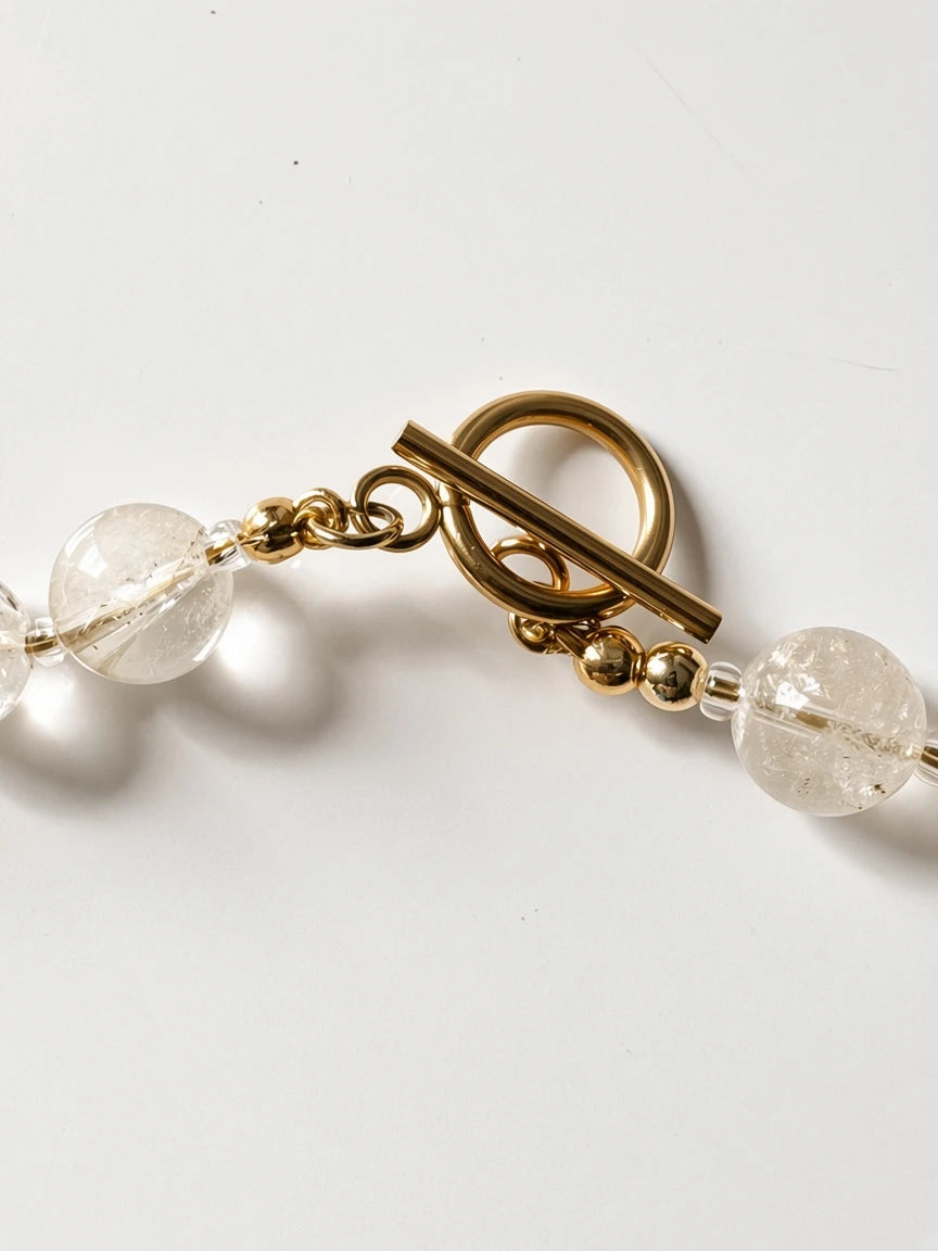 Hue La La Gems statement necklace featuring clear faceted beads and a polished gold-tone metal toggle clasp closure.