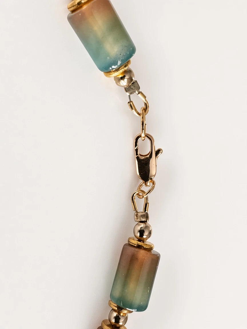 Hue La La Gems statement necklace featuring cylindrical multi-colored gemstone beads and polished gold-tone spacers.