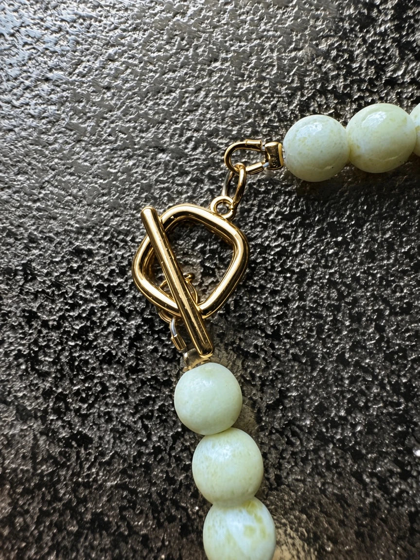 Hue La La Gems handcrafted beaded necklace featuring a polished gold-tone toggle clasp and smooth cream-toned beads.