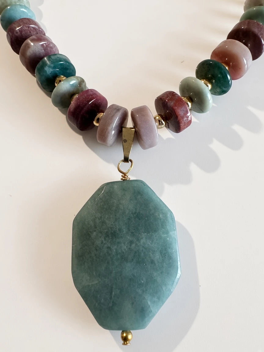 Hue La La Gems statement necklace with multi-colored gemstone beads, gold spacers, and a large green faceted pendant.