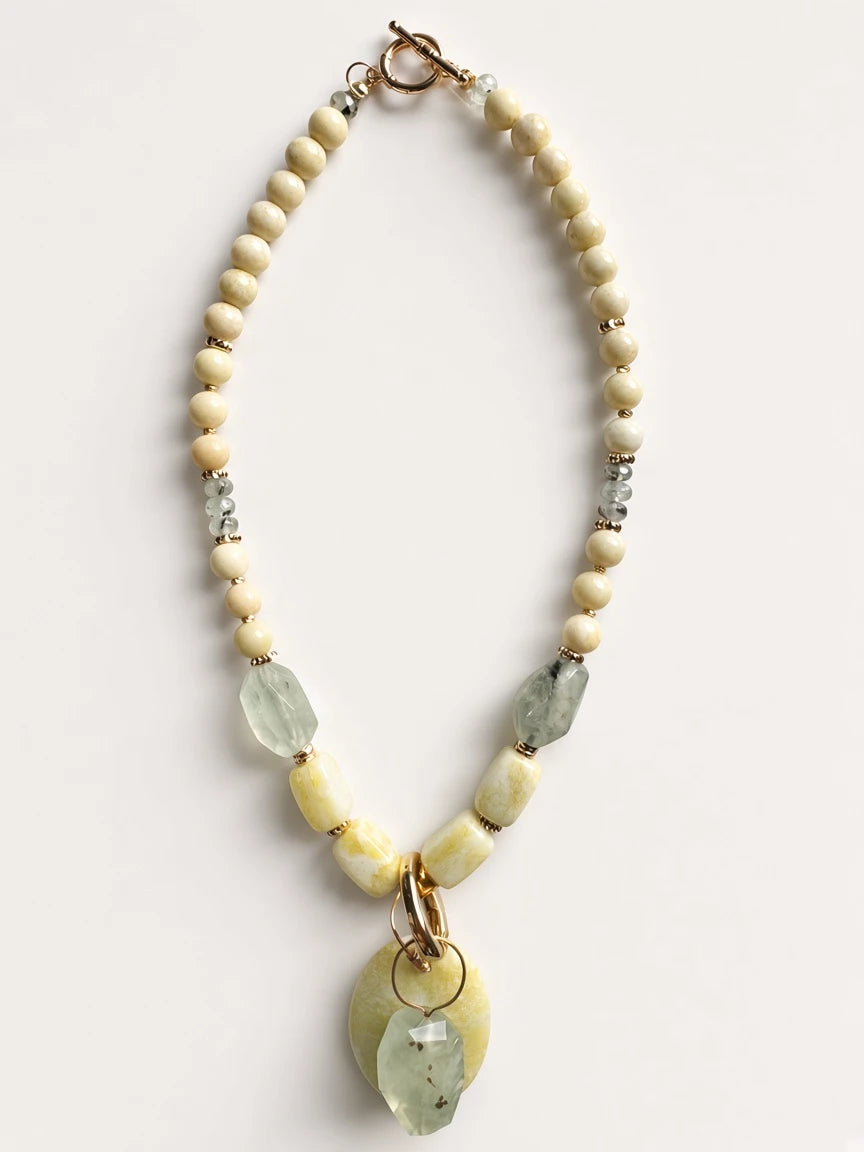 Hue La La Gems handcrafted beaded statement necklace with cream beads, green gemstone drops, and yellow oval pendant.