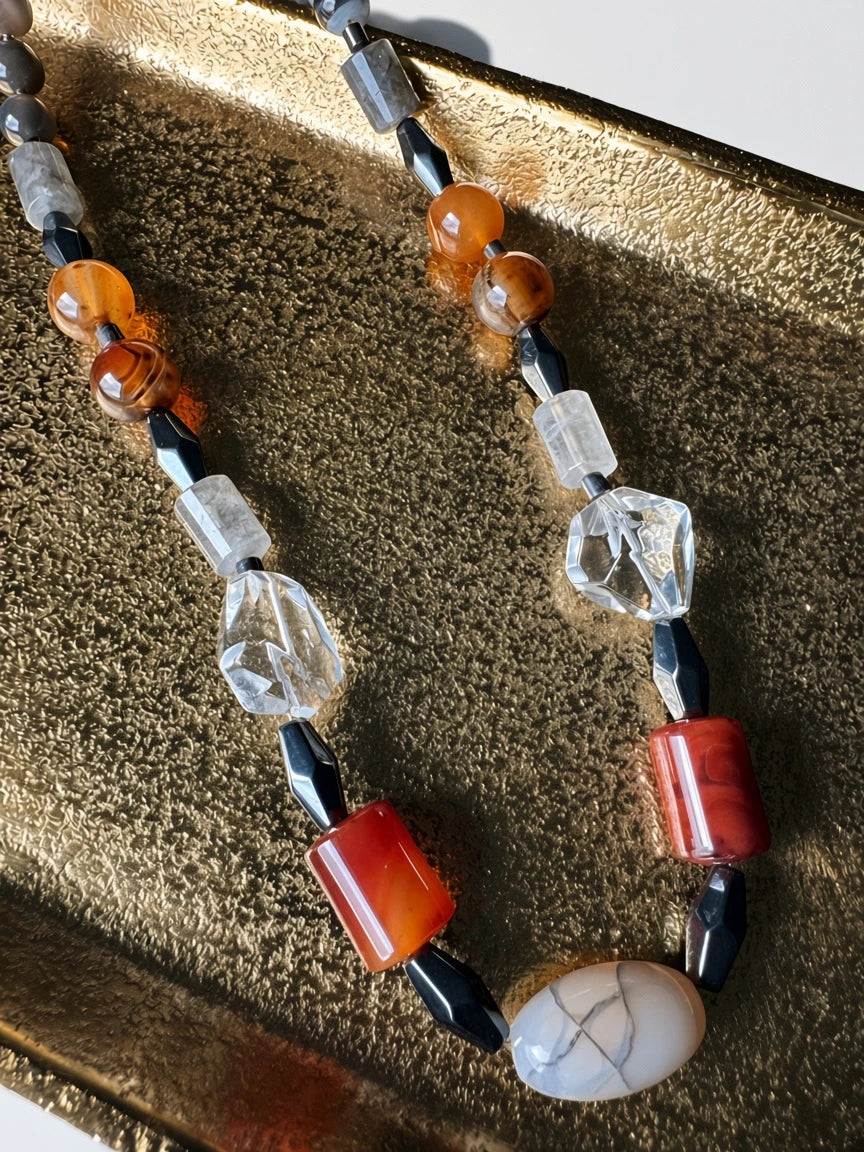 Hue La La Gems artisan statement necklace with carnelian, clear quartz, agate, and obsidian beads on a gold tray.