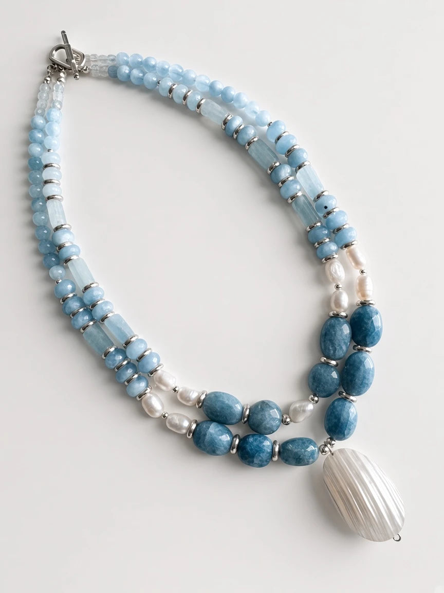 Hue La La Gems multi-strand statement necklace with blue aquamarine beads, freshwater pearls, and a shell pendant.