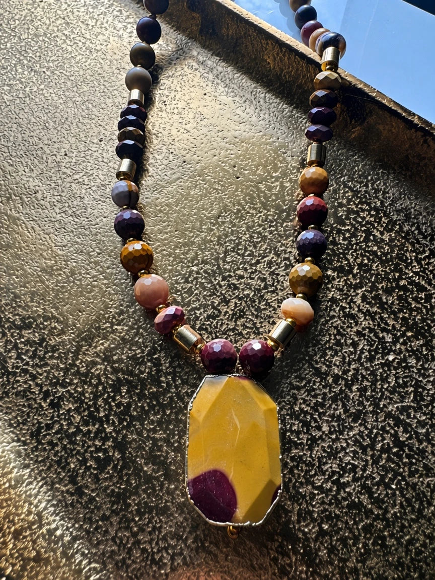Hue La La Gems beaded statement necklace with burgundy, mustard, and peach gemstones and a geometric yellow pendant.