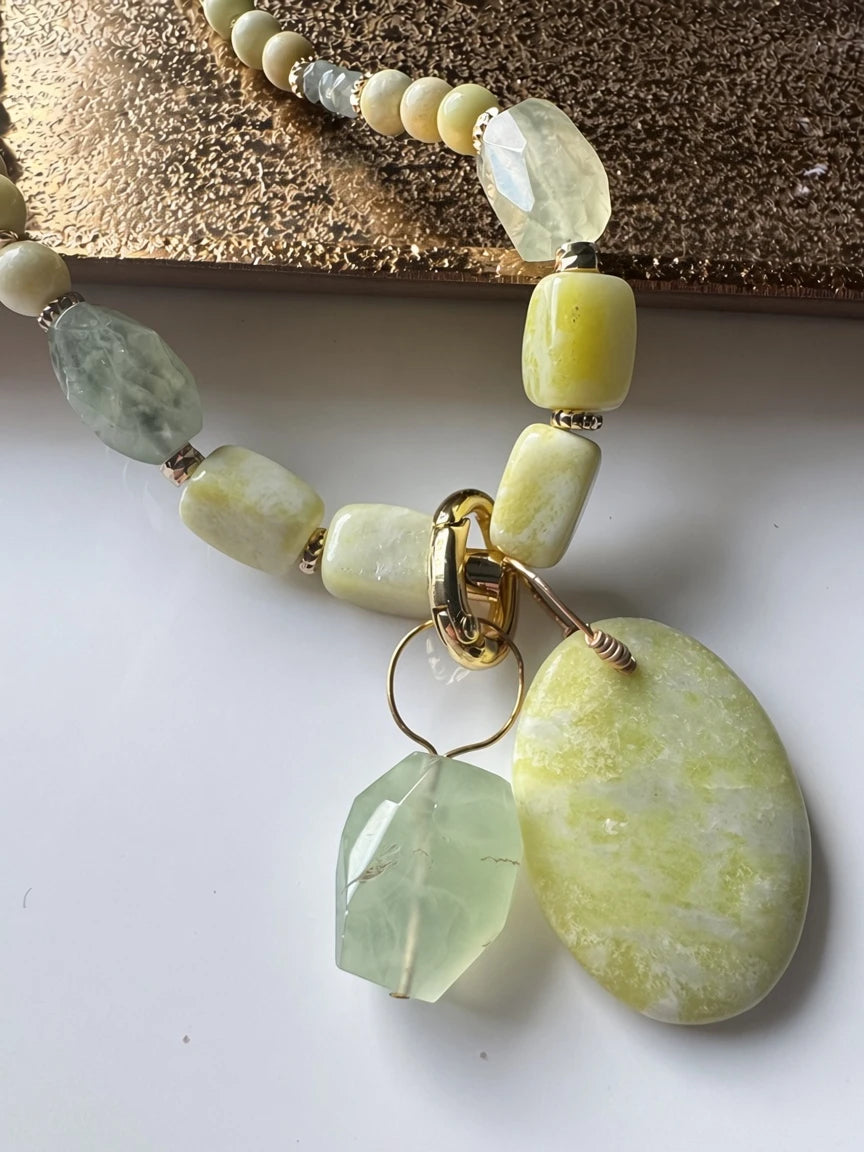 Hue La La Gems handcrafted statement necklace with cream beads, green gemstone drops, and a yellow marbled pendant.