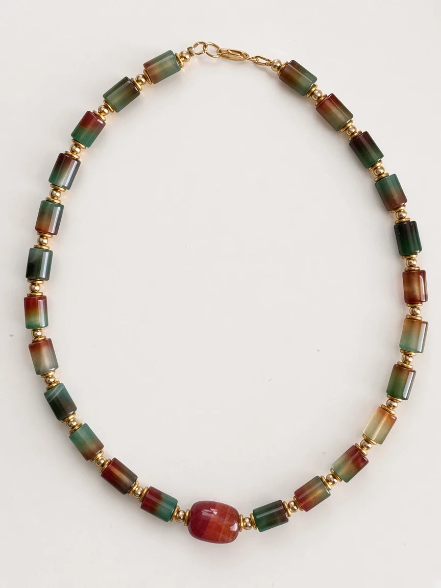 Hue La La Gems statement necklace featuring cylindrical multi-colored gemstone beads and polished gold-tone spacers.