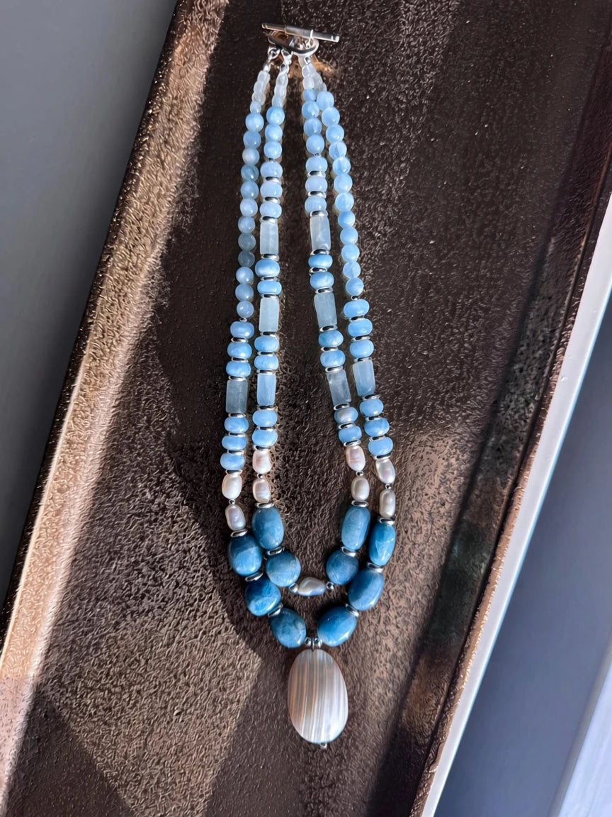Hue La La Gems multi-strand statement necklace with blue aquamarine beads, freshwater pearls, and a shell pendant.