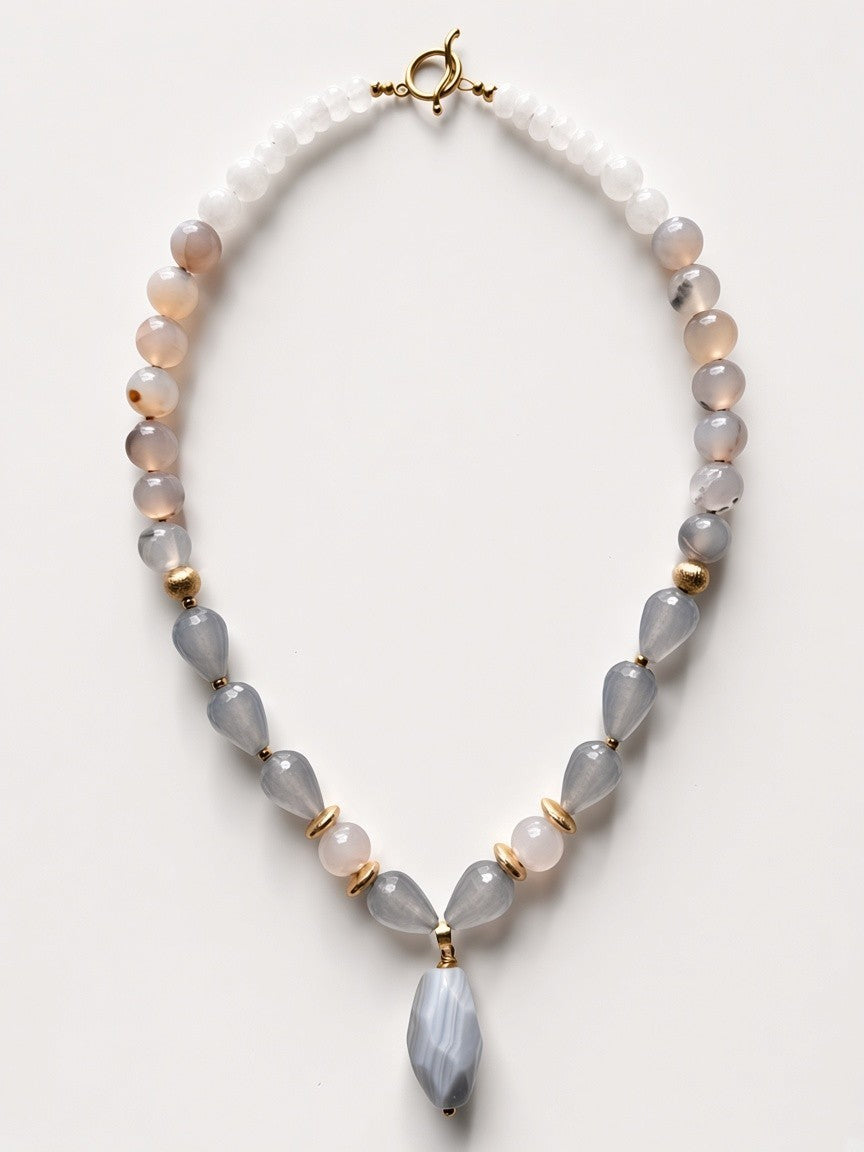 Hue La La Gems statement necklace featuring grey and white gemstone beads with gold-tone spacers and a faceted pendant.