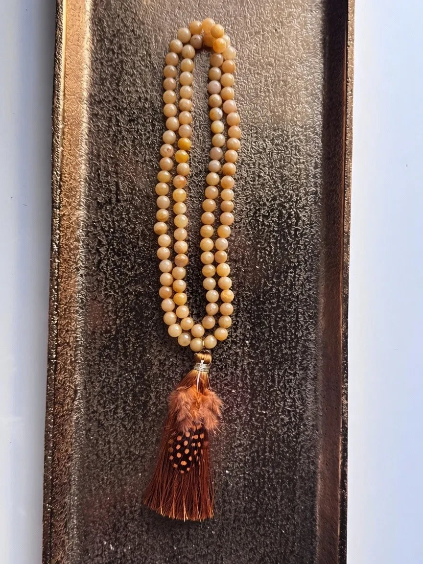 Hue La La Gems artisan beaded necklace featuring yellow gemstone beads and a brown feathered tassel pendant.