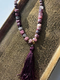 Hue La La Gems statement necklace with plum, mauve, and dusty rose stone beads, gold accents, and a purple silk tassel.