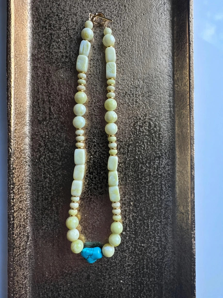 Hue La La Gems beaded necklace with pale yellow-green beads, gold spacers, and a turquoise heart pendant.