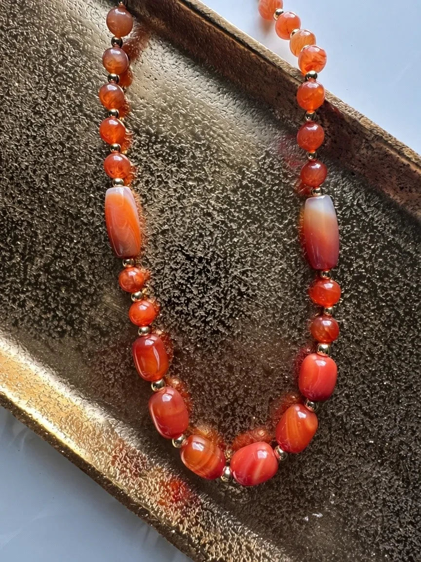 Hue La La Gems artisan beaded necklace featuring vibrant orange carnelian gemstones and gold-toned metal accents.