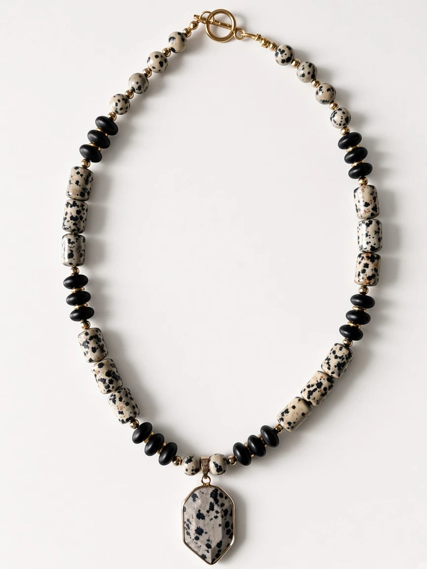 Hue La La Gems statement necklace with dalmatian jasper beads, matte black beads, gold spacers, and geometric pendant.