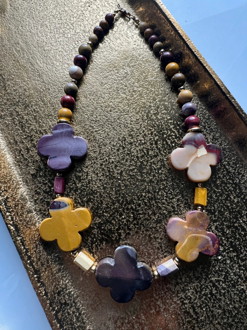 Hue La La Gems floral statement necklace featuring multi-colored natural stone beads in plum, ochre, and earth tones.
