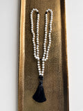 Hue La La Gems mala necklace featuring white moonstone beads, black tourmaline accents, and a soft black tassel.
