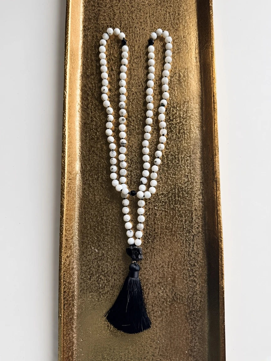 Hue La La Gems mala necklace featuring white moonstone beads, black tourmaline accents, and a soft black tassel.