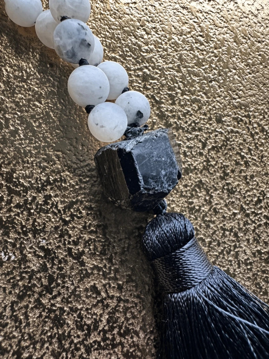 Hue La La Gems mala necklace featuring white moonstone beads, a raw black tourmaline stone, and a soft black tassel.
