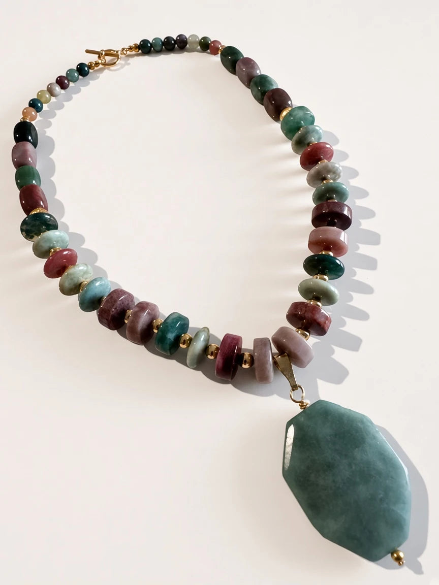 Hue La La Gems beaded statement necklace with multi-colored natural stones, gold spacers, and a large green pendant.