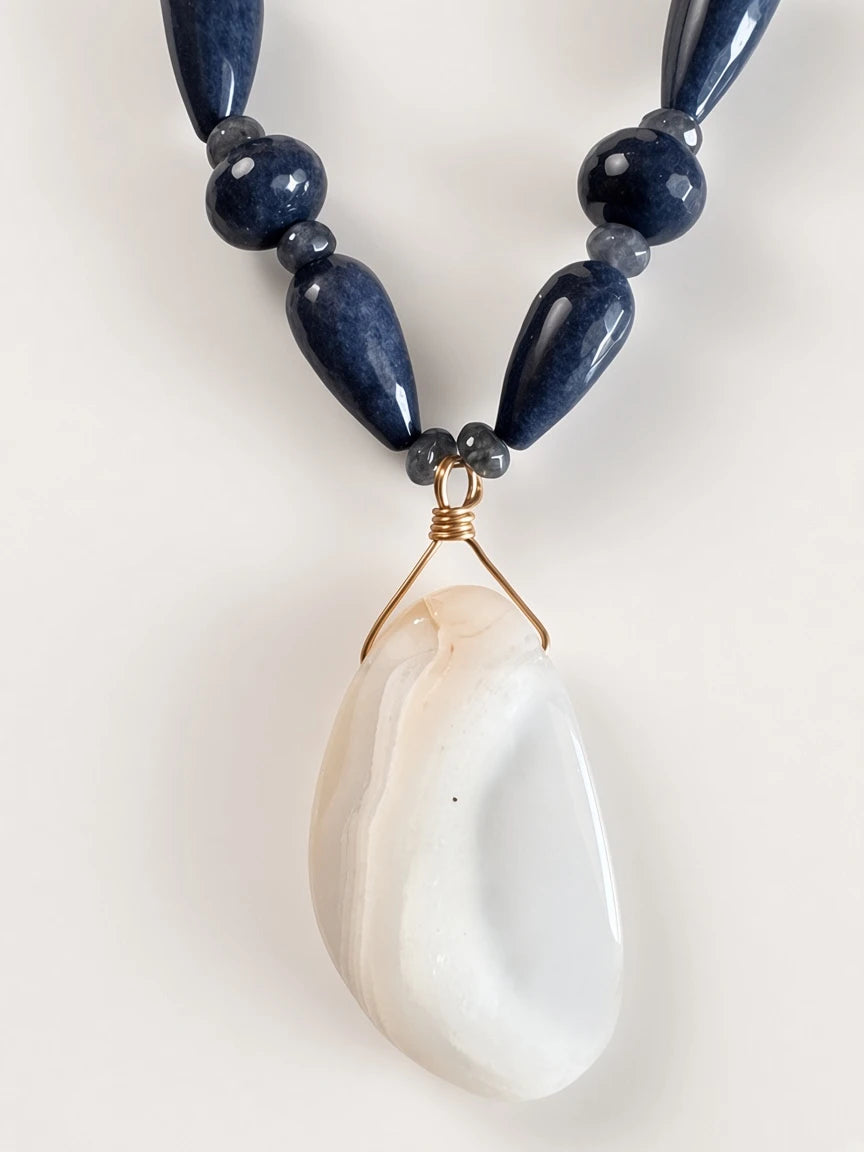 Hue La La Gems artisan necklace featuring navy blue stone beads and a large organic cream stone pendant with gold wire