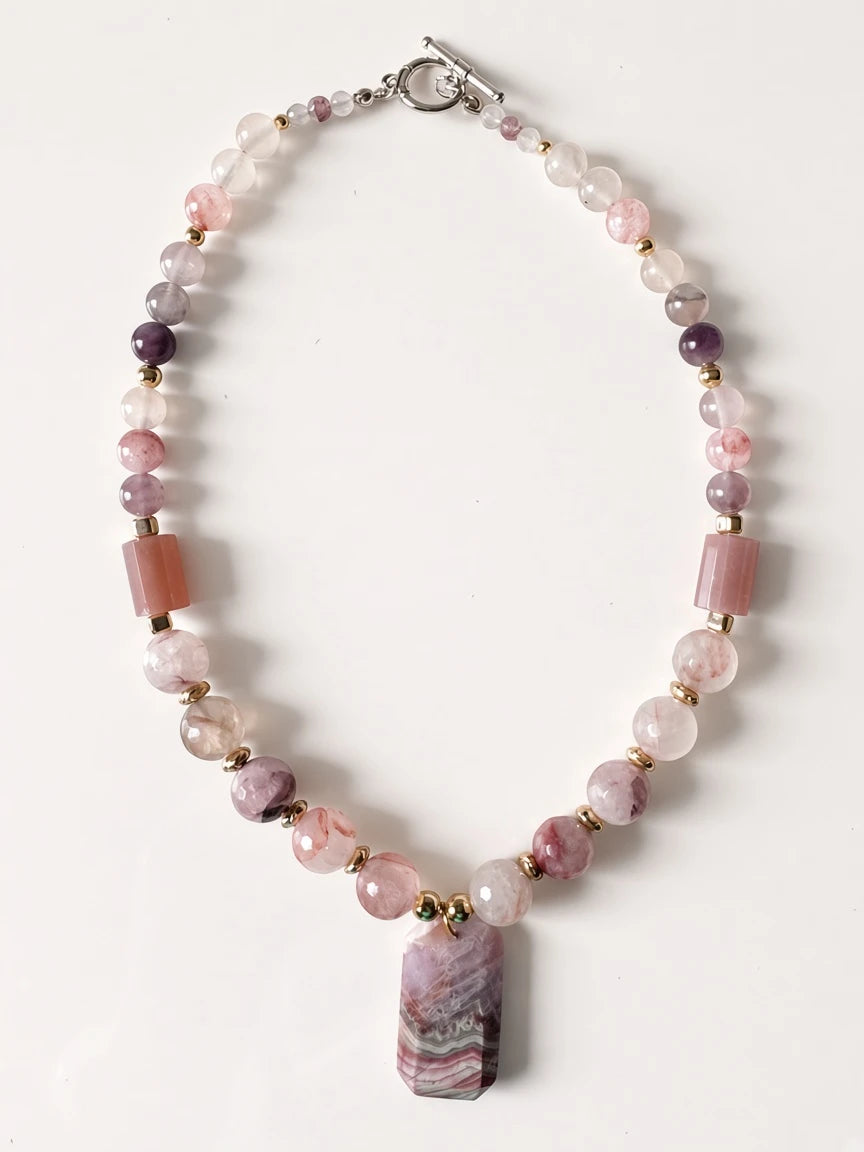 Hue La La Gems beaded statement necklace with pink gemstone beads, gold spacers, and a geometric banded pendant.