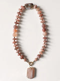 Hue La La Gems statement necklace featuring peach sunstone beads, a baroque pearl, and a gold-framed stone pendant.
