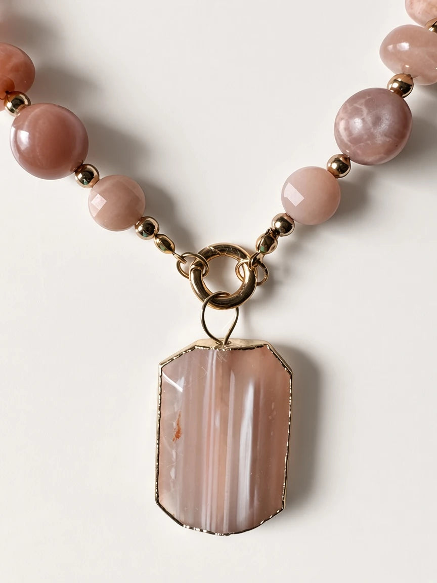 Hue La La Gems statement necklace featuring peach sunstone beads, gold spacers, and a rectangular gold-framed pendant.