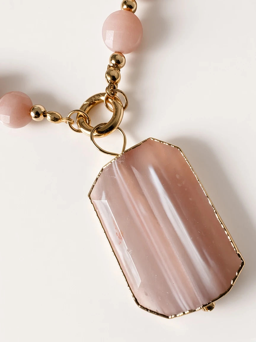 Hue La La Gems statement necklace featuring a faceted peach sunstone pendant in a gold frame with smooth bead accents.