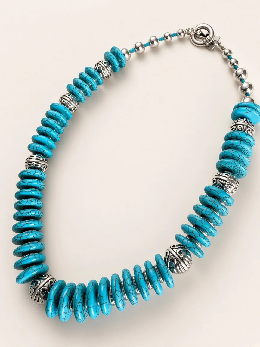 Hue La La Gems statement necklace featuring turquoise disc beads and intricate silver-tone metal spacers with a toggle