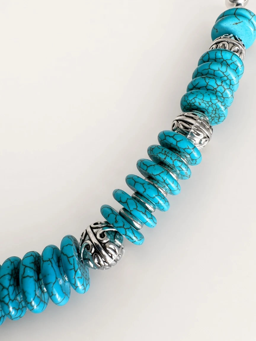 Hue La La Gems statement necklace featuring turquoise disc beads and intricate silver-tone metal spacer accents.