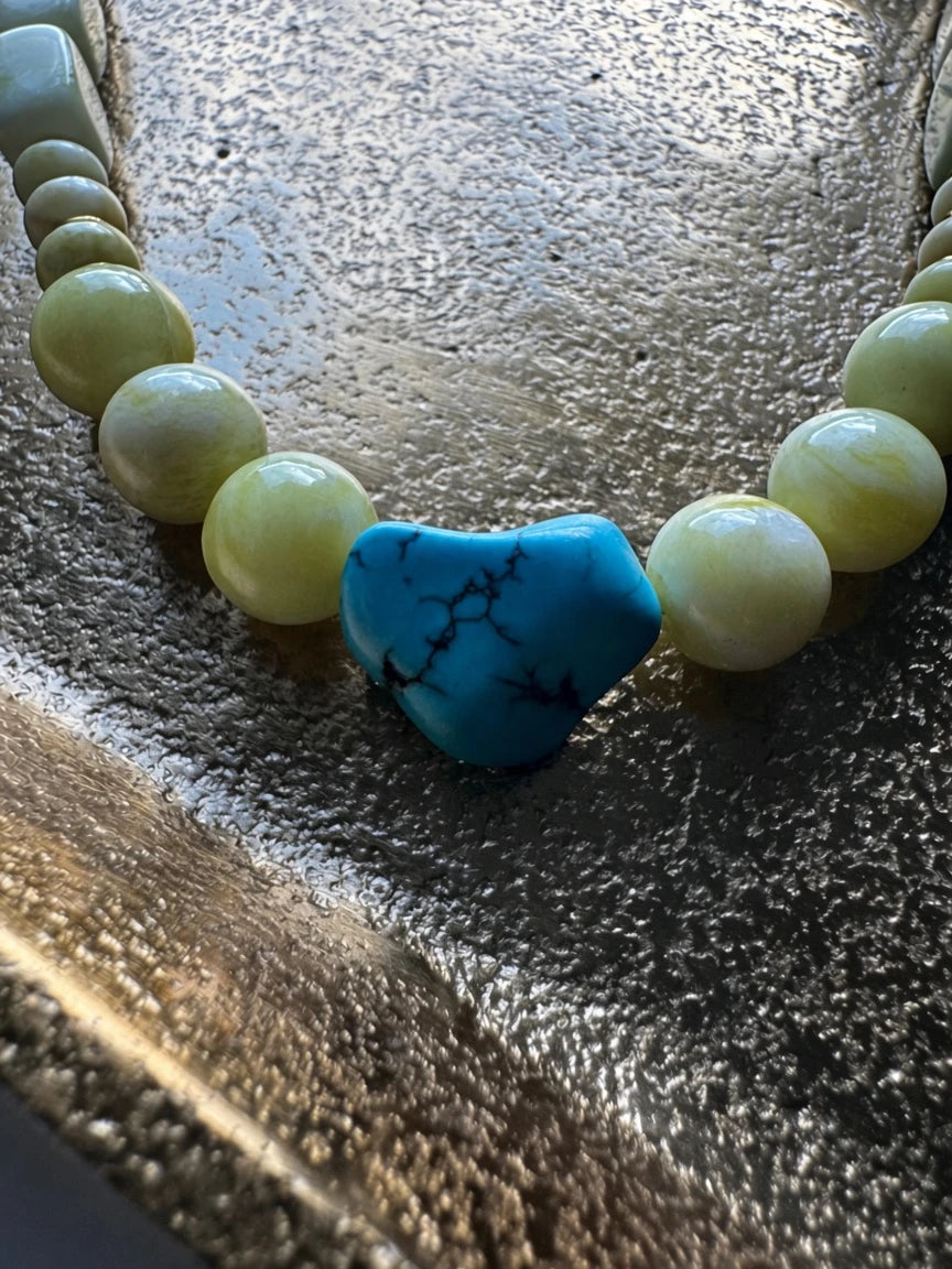 Hue La La Gems handcrafted beaded necklace featuring pale yellow-green beads and a central heart-shaped turquoise stone.