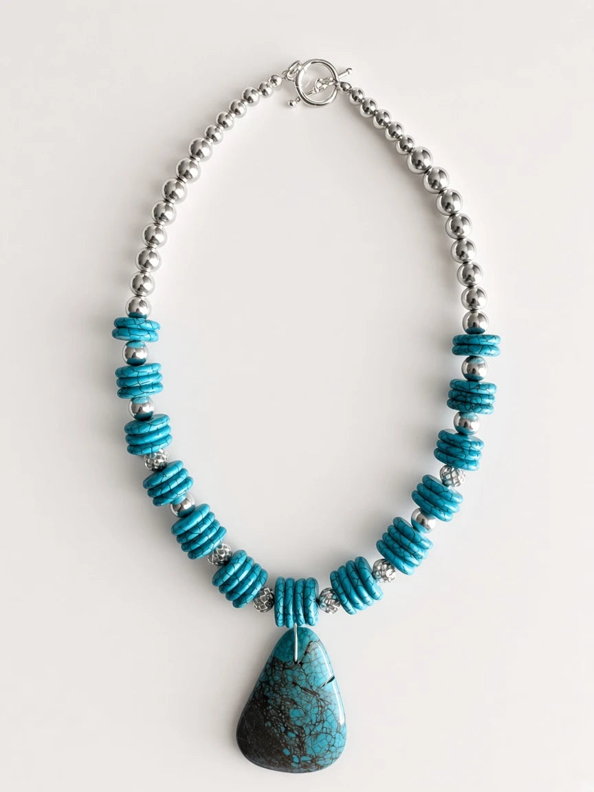 Hue La La Gems turquoise teardrop pendant necklace with disc beads and silver-tone accents on a white background.