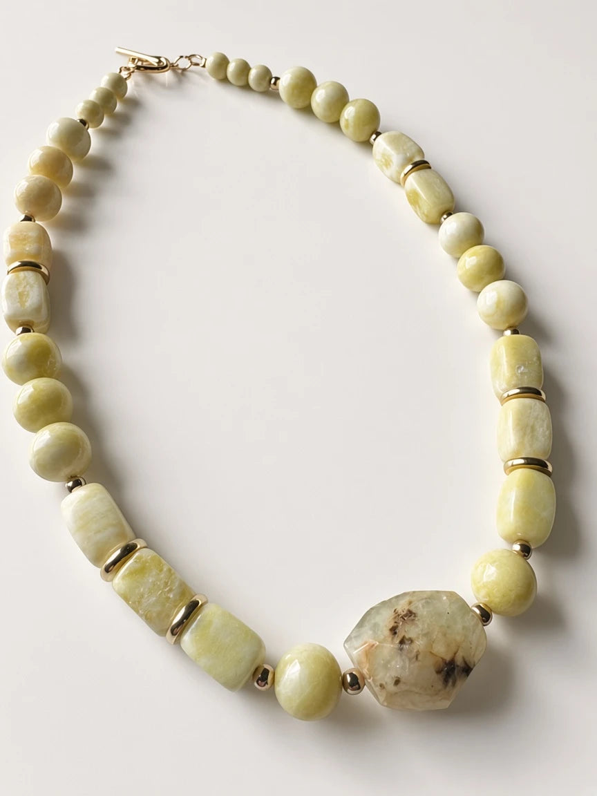 Hue La La Gems beaded statement necklace featuring pale yellow-green stone beads, gold-tone spacers, and a raw focal stone